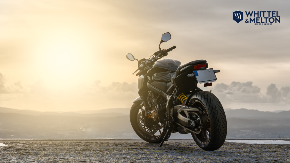 Motocicleta estacionada al atardecer con el logotipo de Whittel & Melton, abogados de lesiones personales en Florida.